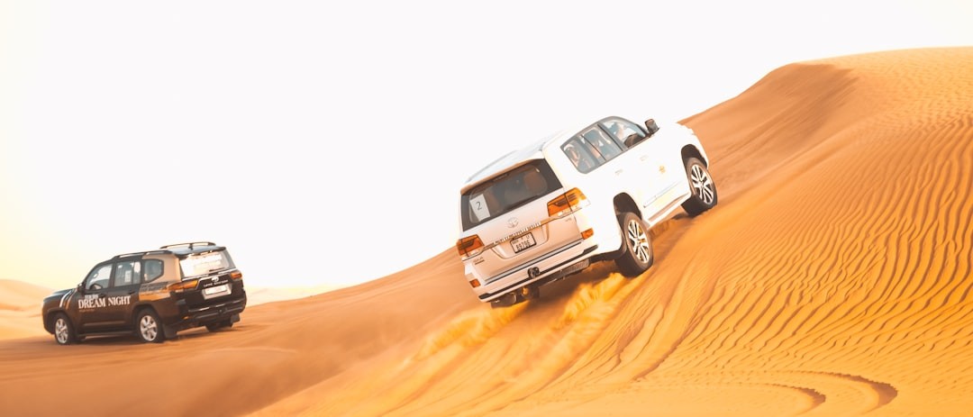 a couple of vehicles driving across a desert in dubai which is called desert safari